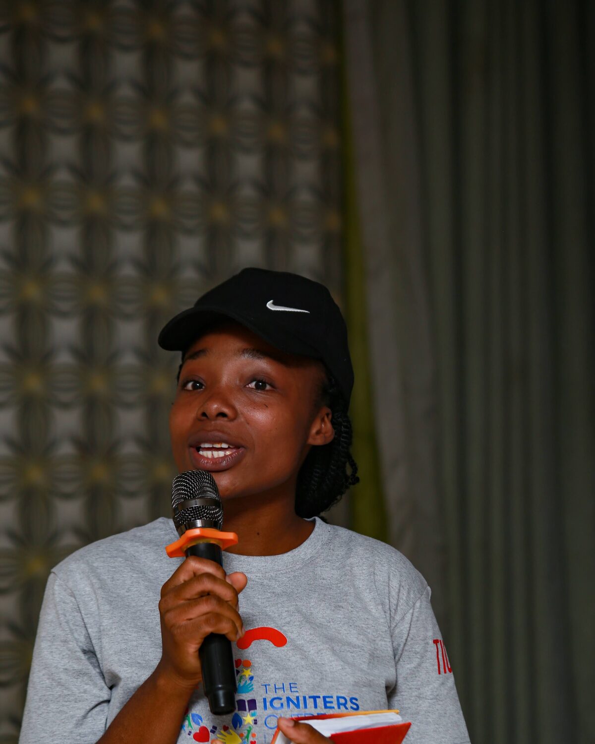 A member speaking into a microphone during an Igniters gathering